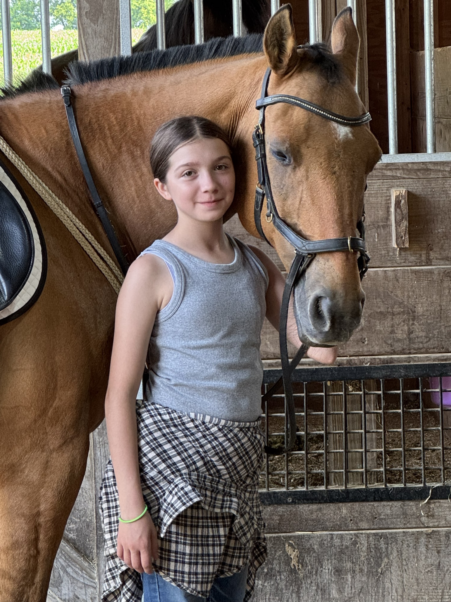 A rider standing with her bay horse in the stable